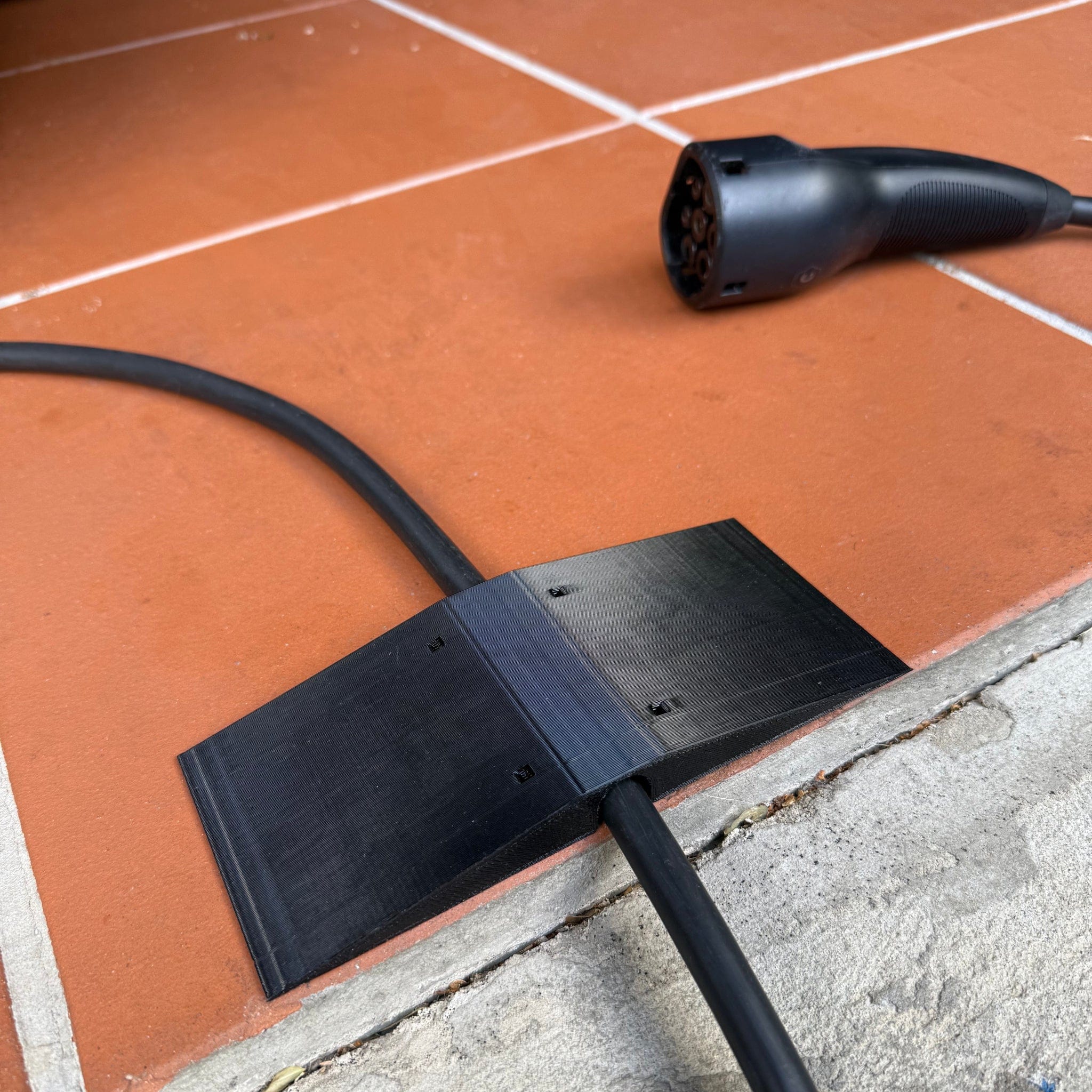 Center-wedge EV charging cable garage door pass-through protector