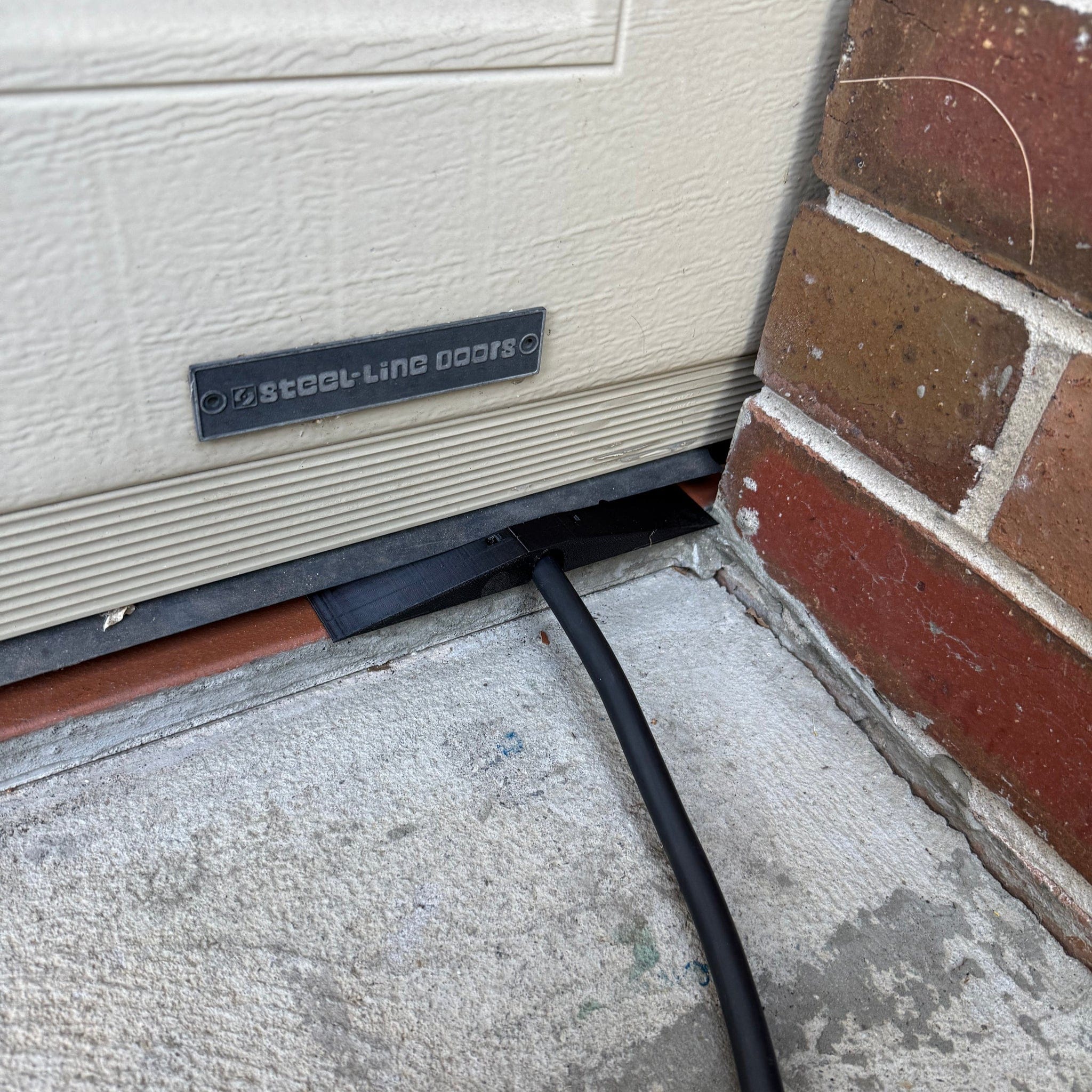 Center-wedge EV charging cable garage door pass-through protector